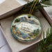A decorative ornament featuring a scenic landscape of Jackson Lake, Colorado, with mountains, pine trees, and a body of water.
