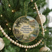 A round ornament hanging on a Christmas tree, featuring an illustration of a historic plantation house surrounded by trees and a pond.