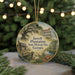 A round ornament with a painting of a historic plantation and house, surrounded by greenery and a string of lights.
