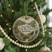 A round ornament hanging on a Christmas tree, featuring a scenic landscape with a waterfall and mountains.