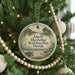 A round ornament hanging on a Christmas tree, featuring a scenic image of a beach and palm trees.