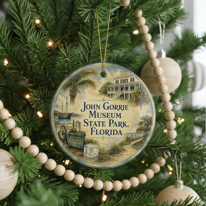 A round ornament hanging on a Christmas tree, featuring an illustration of a building and palm trees, with the text "John Gorrie Museum State Park, Florida" displayed on it.