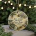 A round ornament with a painting of a house and palm trees, surrounded by Christmas lights and greenery.