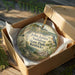 A decorative ornament in a wooden box, featuring a bird and a scenic landscape, with the text "John James Audubon State Park, Kentucky" printed on it.