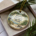A decorative ornament in a box, featuring illustrations of a bird, palm tree, and beach scene, with the text "Jonathan Dickinson State Park, Florida" printed on it.