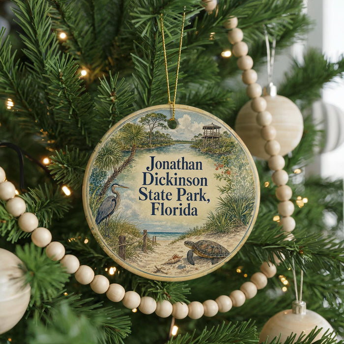 A round ornament hanging on a Christmas tree, featuring an illustration of a beach scene with a bird and a turtle.