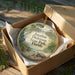 A decorative ornament in a box, featuring a tropical beach scene with palm trees, a bird, and a turtle.