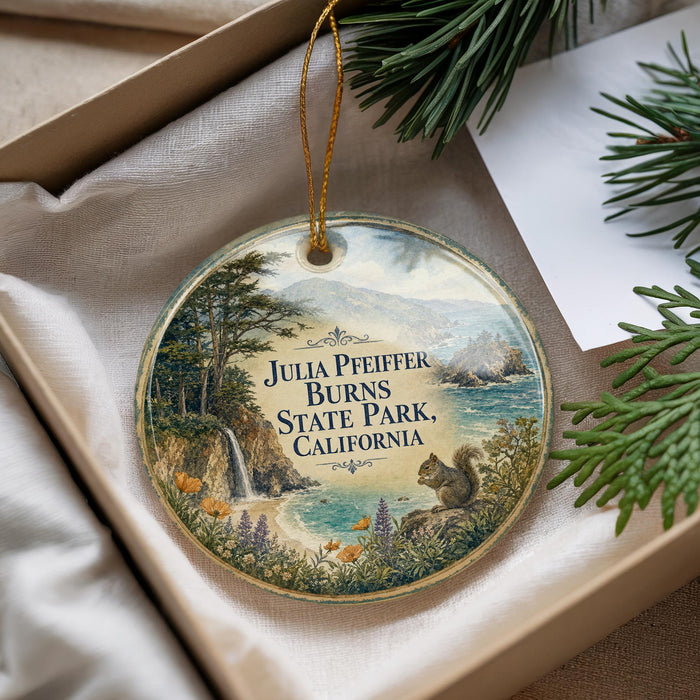 A round ornament with a scenic landscape featuring a waterfall, pine trees, and a squirrel, hanging from a string.
