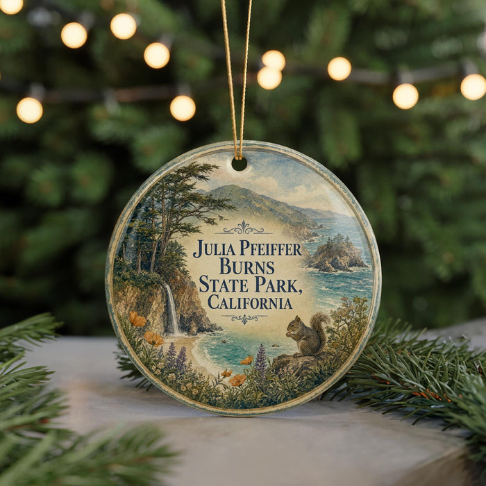 A round ornament with a scenic landscape featuring a waterfall, mountains, and a squirrel, hanging from a string.