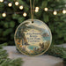 A round ornament with a scenic landscape featuring a waterfall, mountains, and a squirrel, hanging from a string.