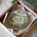 A decorative ornament in a box, featuring a lighthouse and a bird, with the text "Kaena Point State Park, Hawaii" printed on it.