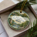 A decorative ornament in a box, featuring a scenic image of the Kankakee River State Park in Illinois.