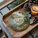 A wooden tray with a decorative ornament featuring a scenic image of Kaw River State Park, Kansas, and pine cones.