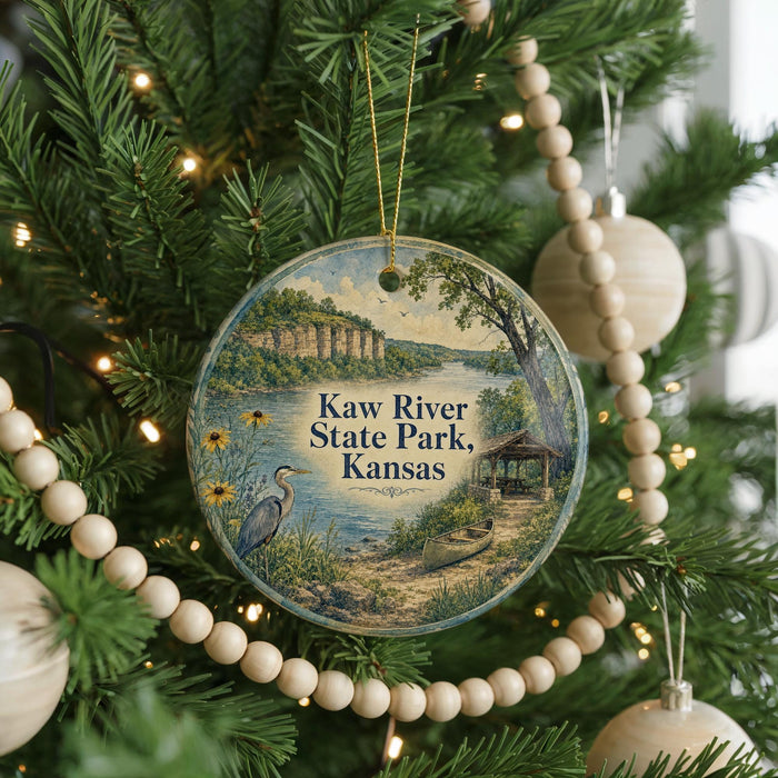 A circular ornament hanging on a Christmas tree, featuring a scenic landscape with a lake, mountains, and a bird.