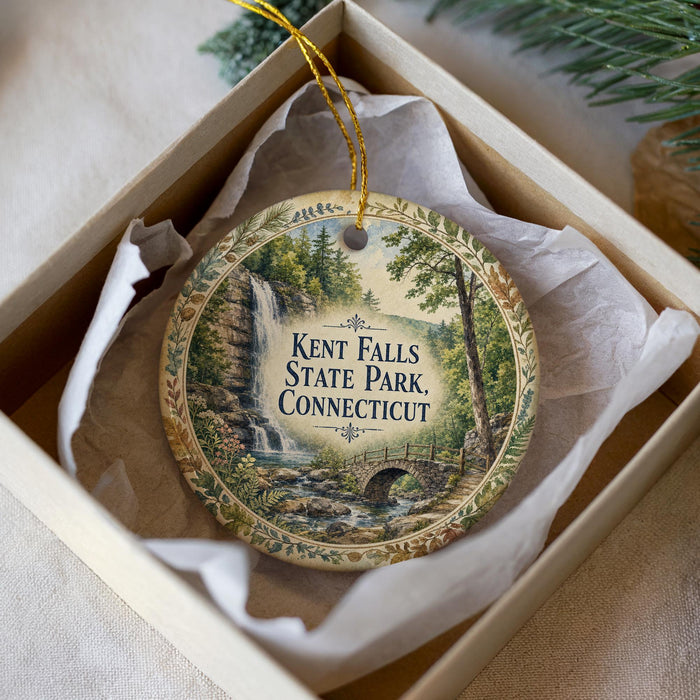 A decorative ornament in a box, featuring a scenic image of Kent Falls State Park in Connecticut.