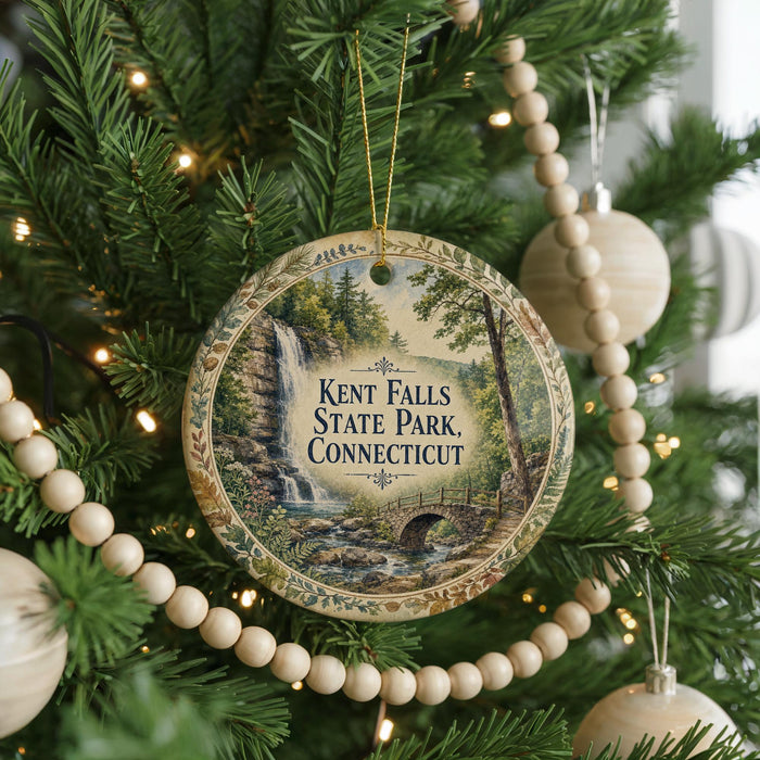 A round ornament hanging on a Christmas tree, featuring a scenic image of Kent Falls State Park in Connecticut.