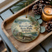 A decorative ornament featuring a scenic view of Kincaid Lake State Park, Kentucky, with a bench and pine cones on a wooden tray.