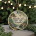 A round ornament with a scenic landscape of Kentucky State Park, featuring a bridge, trees, and a river, is displayed against a blurred background of Christmas lights.