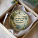 A decorative ornament in a box, featuring a scenic landscape with a lake, trees, and birds.