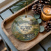 A decorative ornament featuring a scenic image of Lake Ahwatani State Park in Iowa, with a candle and pine cones on a wooden tray.