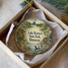 A decorative ornament in a box, featuring a scenic landscape with a lake, trees, and a cabin, along with the text "Lake Bronson State Park, Minnesota".