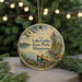 A round ornament with a scenic lake and forest landscape, featuring a boat on the water and a dock in the foreground.