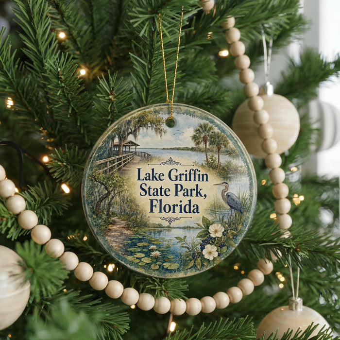A round ornament hanging on a Christmas tree, featuring a scenic image of Lake Griffin State Park in Florida.