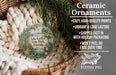 Ceramic ornaments, featuring a round ornament with a landscape design, are displayed in a basket with greenery.