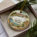 A decorative ornament with a scenic image of Lake Havasu State Park in Arizona, featuring palm trees, mountains, and a bird.