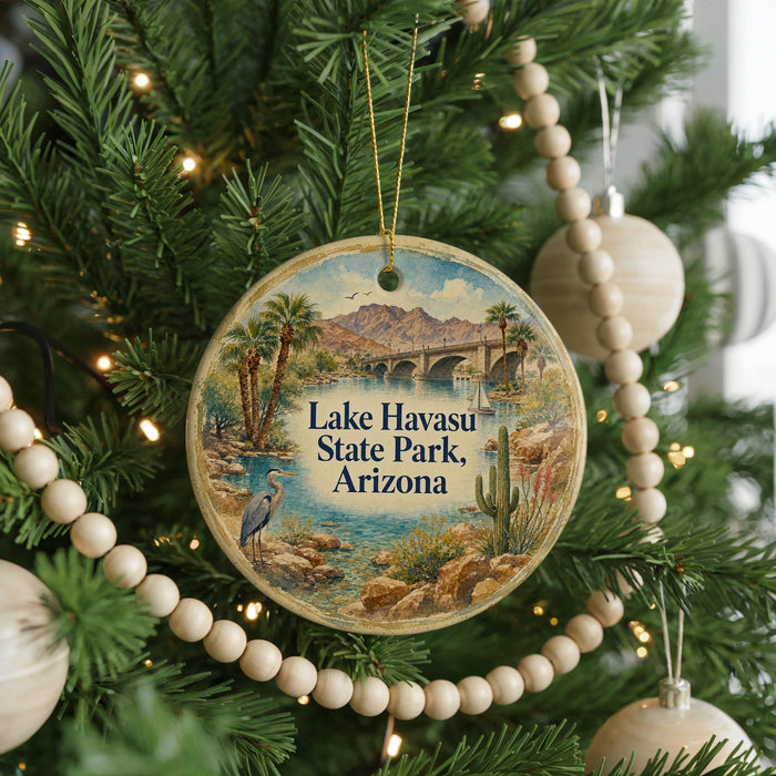 A round ornament hanging on a Christmas tree, featuring a scenic landscape with mountains, palm trees, and a bird.