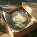 A decorative ornament in a wooden box, featuring a scenic landscape with a lake, trees, and a canoe, with the text "Lake Louise State Park, Minnesota" printed on it.