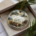A decorative ornament with a scenic image of Lake Vermilion, Minnesota, surrounded by pine branches.