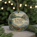 A decorative ornament featuring a scenic lake surrounded by trees and a castle, with the text "Lake Waramaug State Park, Connecticut" displayed prominently.