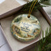 A decorative ornament with a scenic image of Lakelands Trail State Park, Michigan, featuring a deer, a bird, and a path surrounded by trees and grass.