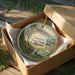 A decorative ornament in a wooden box, featuring a scenic landscape with a waterfall and forest, with the text "Limekiln State Park, California" printed on it.