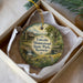 A decorative ornament in a box, featuring a scenic image of a log cabin surrounded by nature, with the text "Lincoln Homestead State Park, Kentucky" printed on it.