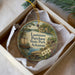 A decorative ornament in a box, featuring a scenic landscape with a river, a boat, and a cabin, along with the text "Louisiana Purchase State Park, Arkansas".