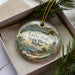 A decorative ornament with a scenic landscape of Lucky Peak State Park, Idaho, featuring a lake, mountains, pine trees, and a boat on the water.
