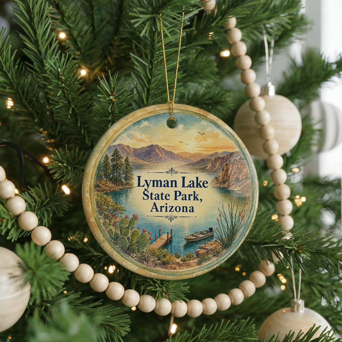 A round ornament hanging on a Christmas tree, featuring a scenic landscape with mountains, a lake, and a boat.
