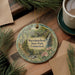 A decorative ornament featuring a scenic image of the state park in Connecticut, surrounded by pine branches and a cup of coffee on a wooden surface.
