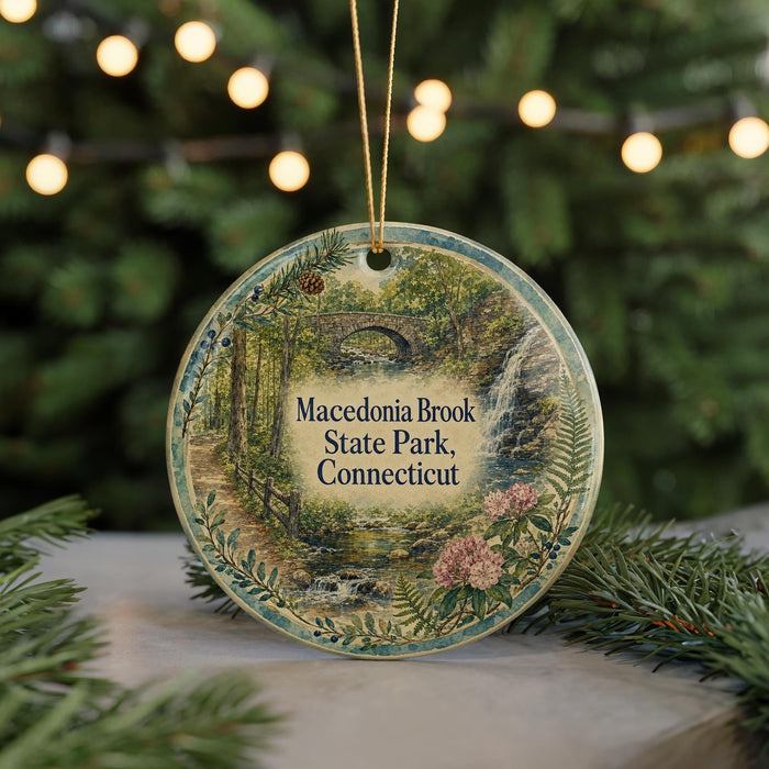 A round ornament with a scenic image of a forest and a waterfall, hanging from a string.