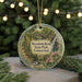 A round ornament with a scenic image of a forest and a waterfall, hanging from a string.
