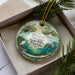 A decorative ornament featuring a manatee and a scenic landscape, with the text "Manatee Springs State Park, Florida" displayed prominently.