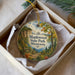 A decorative ornament in a box, featuring a scenic landscape with a path, trees, and a lake, with the text "Maplewood State Park, Minnesota" prominently displayed.