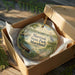 A decorative ornament in a wooden box, featuring a scenic landscape with a lake, boat, and birds, along with the text "Martinak State Park, Maryland".