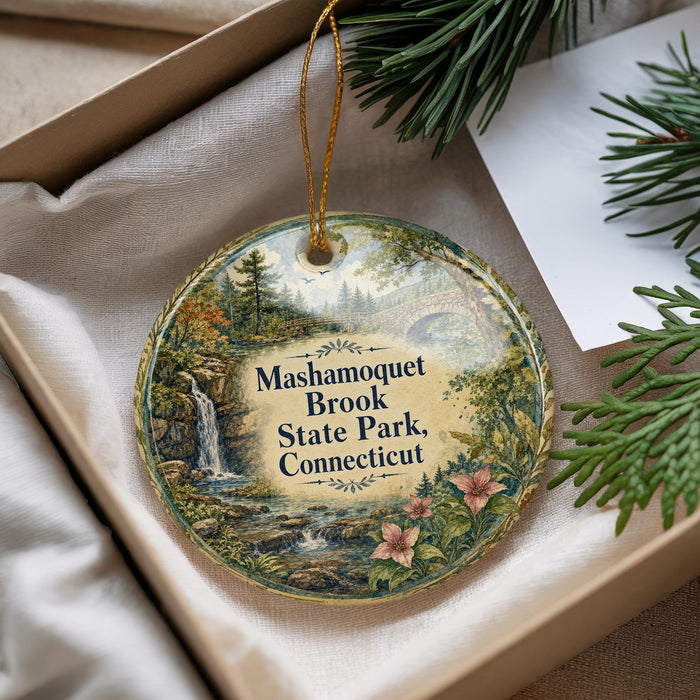 A decorative ornament with a scenic landscape of Mashamquet Brook State Park, Connecticut, featuring a waterfall and pine trees.