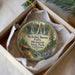 A decorative ornament in a white box, featuring an illustration of a waterfall and a cabin, with the text "McArthur-Burney Falls Memorial State Park, California" printed on it.