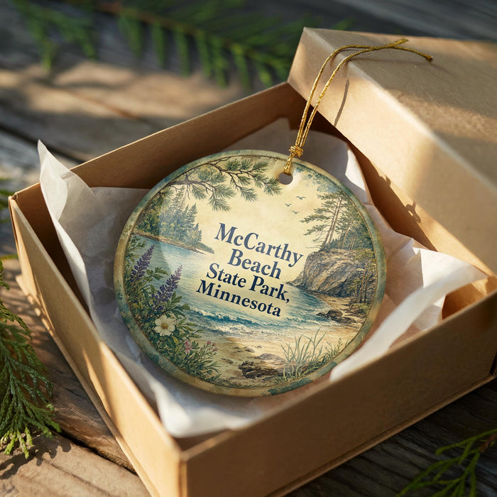 A decorative ornament in a wooden box, featuring a scenic landscape with pine trees, a lake, and mountains.