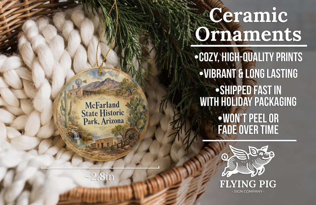 Ceramic ornaments, featuring a decorative piece with a landscape scene and text, are displayed in a basket with greenery.