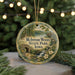 A round ornament with a scenic image of a forest and a lake, surrounded by Christmas lights.